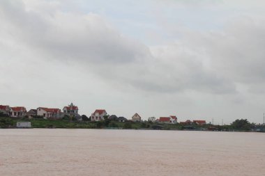 Nehir Vietnam 'da. Nehirde kayıklar ve gemiler, kıyılarda kırsal köyler, balık kafesleri, sebze tarlaları var.