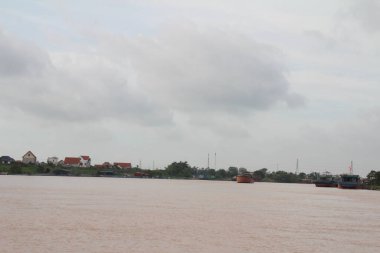 Nehir Vietnam 'da. Nehirde kayıklar ve gemiler, kıyılarda kırsal köyler, balık kafesleri, sebze tarlaları var.