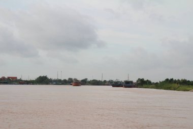 Nehir Vietnam 'da. Nehirde kayıklar ve gemiler, kıyılarda kırsal köyler, balık kafesleri, sebze tarlaları var.
