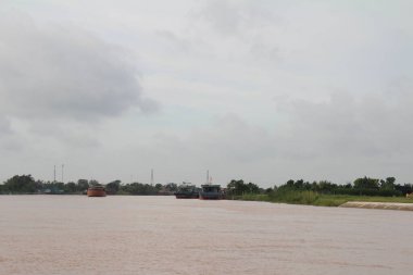 Nehir Vietnam 'da. Nehirde kayıklar ve gemiler, kıyılarda kırsal köyler, balık kafesleri, sebze tarlaları var.