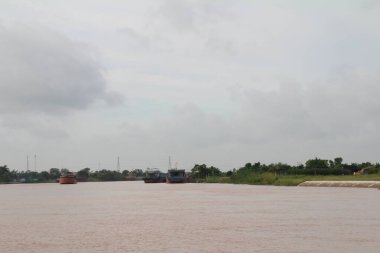 Nehir Vietnam 'da. Nehirde kayıklar ve gemiler, kıyılarda kırsal köyler, balık kafesleri, sebze tarlaları var.