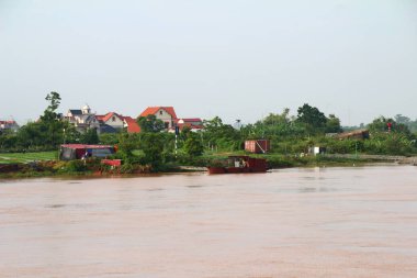 Nehir Vietnam 'da. Nehirde kayıklar ve gemiler, kıyılarda kırsal köyler, balık kafesleri, sebze tarlaları var.