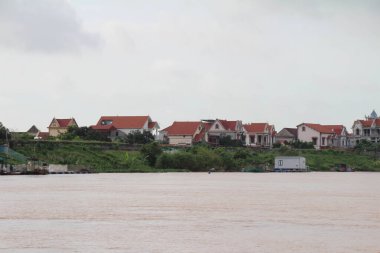 Nehir Vietnam 'da. Nehirde kayıklar ve gemiler, kıyılarda kırsal köyler, balık kafesleri, sebze tarlaları var.