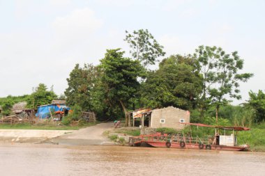 Nehir Vietnam 'da. Nehirde kayıklar ve gemiler, kıyılarda kırsal köyler, balık kafesleri, sebze tarlaları var.