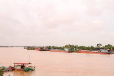 Nehir Vietnam 'da. Nehirde kayıklar ve gemiler, kıyılarda kırsal köyler, balık kafesleri, sebze tarlaları var.
