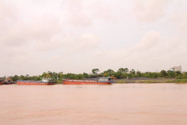 Nehir Vietnam 'da. Nehirde kayıklar ve gemiler, kıyılarda kırsal köyler, balık kafesleri, sebze tarlaları var.