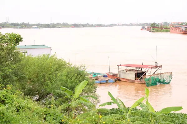Nehir Vietnam 'da. Nehirde kayıklar ve gemiler, kıyılarda kırsal köyler, balık kafesleri, sebze tarlaları var.