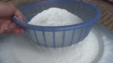 Çiftçinin eli un temizlemek için sepeti kullanıyor.