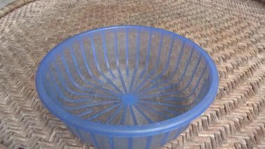 Çiftçinin eli un temizlemek için sepeti kullanıyor.