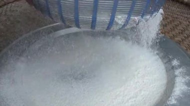 Çiftçinin eli un temizlemek için sepeti kullanıyor.