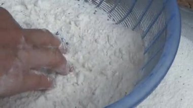 Çiftçinin eli un temizlemek için sepeti kullanıyor.