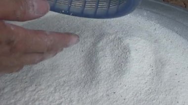 Çiftçinin eli un temizlemek için sepeti kullanıyor.