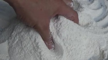 Çiftçinin eli un temizlemek için sepeti kullanıyor.