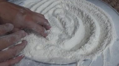 Çiftçinin eli un temizlemek için sepeti kullanıyor.