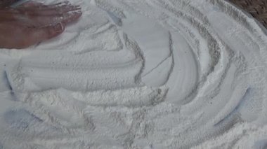 Çiftçinin eli un temizlemek için sepeti kullanıyor.