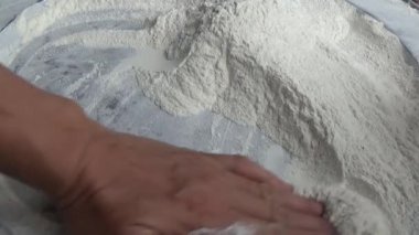 Çiftçinin eli un temizlemek için sepeti kullanıyor.