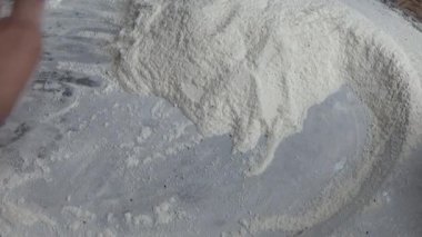 Çiftçinin eli un temizlemek için sepeti kullanıyor.