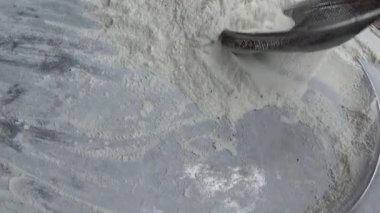 Çiftçinin eli un temizlemek için sepeti kullanıyor.