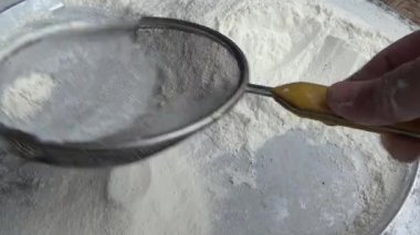 Çiftçinin eli un temizlemek için sepeti kullanıyor.