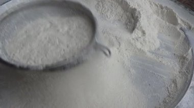 Çiftçinin eli un temizlemek için sepeti kullanıyor.