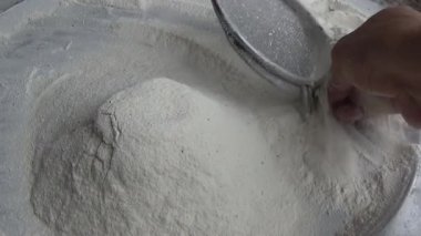 Çiftçinin eli un temizlemek için sepeti kullanıyor.