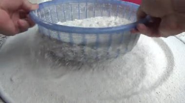 Çiftçinin eli un temizlemek için sepeti kullanıyor.