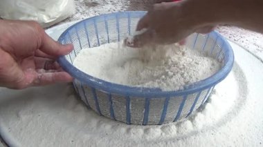 Çiftçinin eli un temizlemek için sepeti kullanıyor.