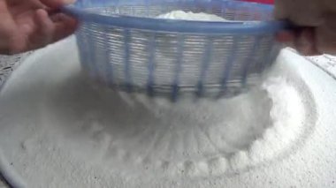 Çiftçinin eli un temizlemek için sepeti kullanıyor.