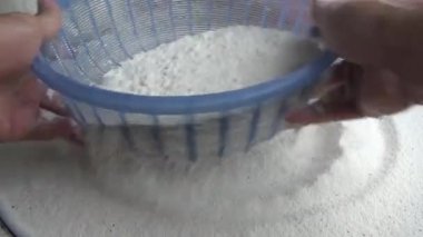 Çiftçinin eli un temizlemek için sepeti kullanıyor.