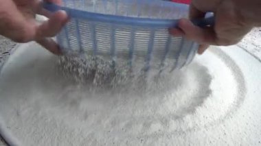 Çiftçinin eli un temizlemek için sepeti kullanıyor.