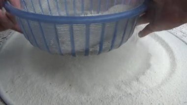 Çiftçinin eli un temizlemek için sepeti kullanıyor.