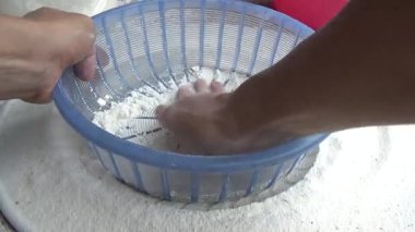 Çiftçinin eli un temizlemek için sepeti kullanıyor.