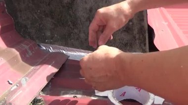 Adam damlayan çatıyı kapatmak için koli bandı kullanıyor.