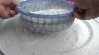 Çiftçinin eli un temizlemek için sepeti kullanıyor.