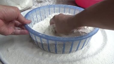 Çiftçinin eli un temizlemek için sepeti kullanıyor.