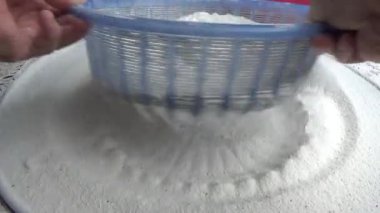 Çiftçinin eli un temizlemek için sepeti kullanıyor.