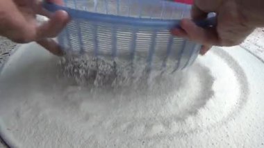 Çiftçinin eli un temizlemek için sepeti kullanıyor.