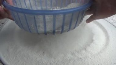 Çiftçinin eli un temizlemek için sepeti kullanıyor.