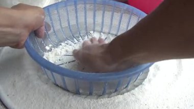 Çiftçinin eli un temizlemek için sepeti kullanıyor.