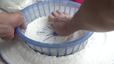 Çiftçinin eli un temizlemek için sepeti kullanıyor.