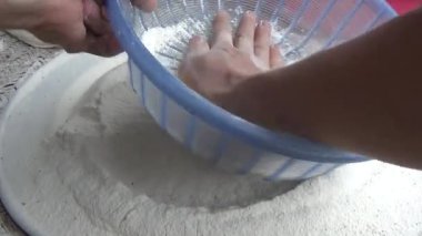 Çiftçinin eli un temizlemek için sepeti kullanıyor.