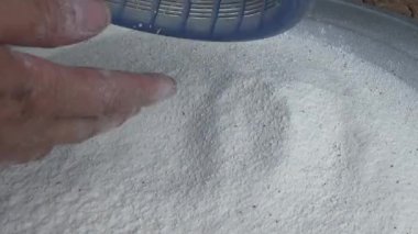 Çiftçinin eli un temizlemek için sepeti kullanıyor.