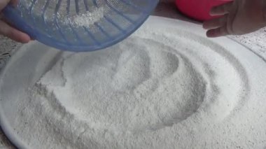 Çiftçinin eli un temizlemek için sepeti kullanıyor.