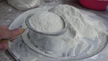 Çiftçinin eli un temizlemek için sepeti kullanıyor.