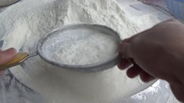 Çiftçinin eli un temizlemek için sepeti kullanıyor.