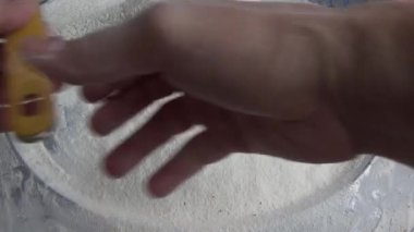 Çiftçinin eli un temizlemek için sepeti kullanıyor.