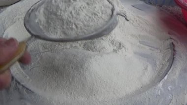 Çiftçinin eli un temizlemek için sepeti kullanıyor.