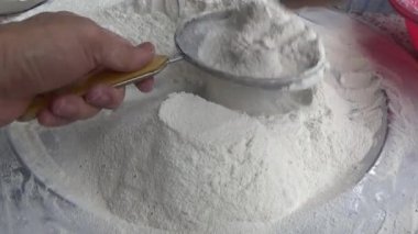 Çiftçinin eli un temizlemek için sepeti kullanıyor.