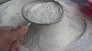 Çiftçinin eli un temizlemek için sepeti kullanıyor.