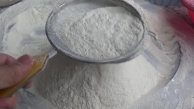 Çiftçinin eli un temizlemek için sepeti kullanıyor.